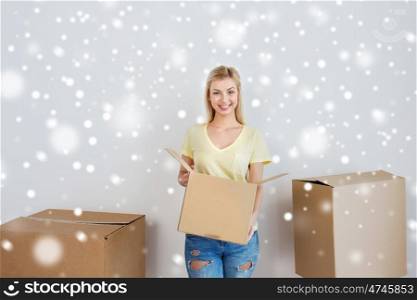 moving, delivery, housing, accommodation and people concept - smiling young woman with cardboard box at home over snow