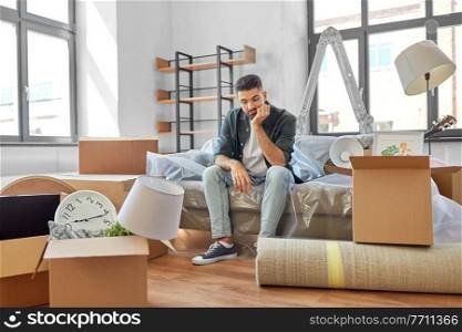 moving, eviction and real estate concept - sad man with boxes at new home. sad man with boxes moving to new home