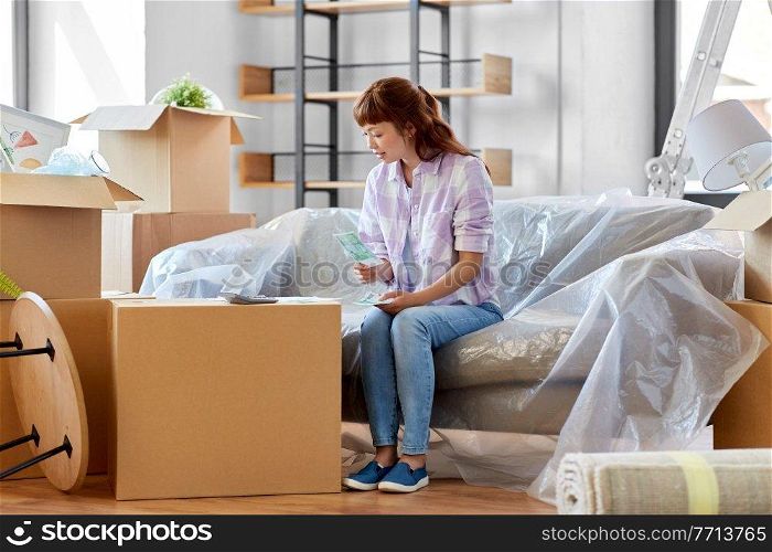 moving, finances and real estate concept - asian woman with money, bills and calculator at new home. asian woman moving to new home and counting money