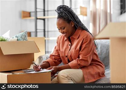 moving, finances and real estate concept - happy smiling woman with bills and calculator at new home. woman with bills and calculator moving to new home