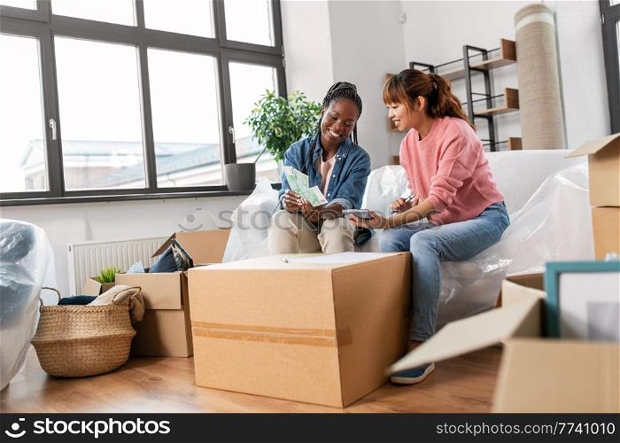 moving, finances and real estate concept - happy smiling women with money, bills and calculator at new home. women moving to new home and counting money