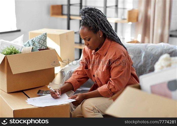 moving, finances and real estate concept - woman with bills and calculator at new home. woman with bills and calculator moving to new home