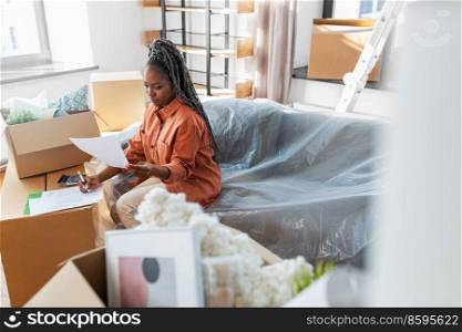 moving, finances and real estate concept - woman with bills and calculator at new home. woman with bills and calculator moving to new home