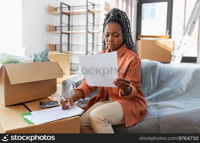 moving, finances and real estate concept - woman with bills and calculator at new home. woman with bills and calculator moving to new home