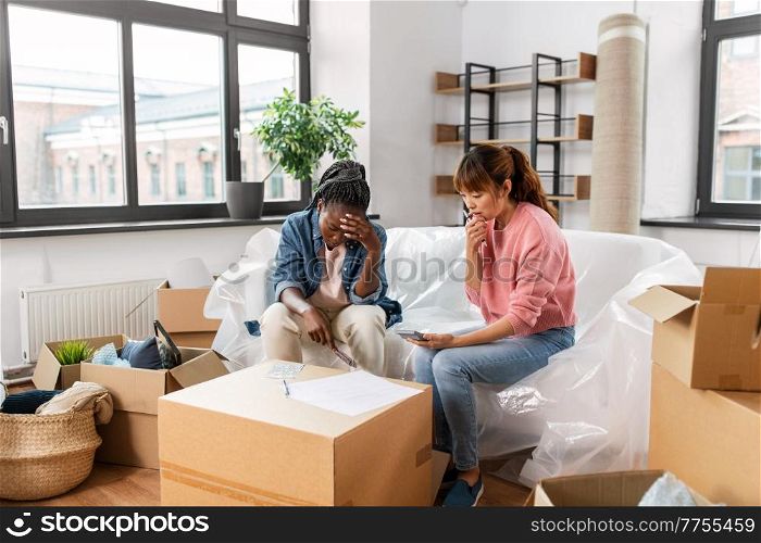 moving, finances and real estate concept - women with money, bills and calculator at new home. women moving to new home and counting money