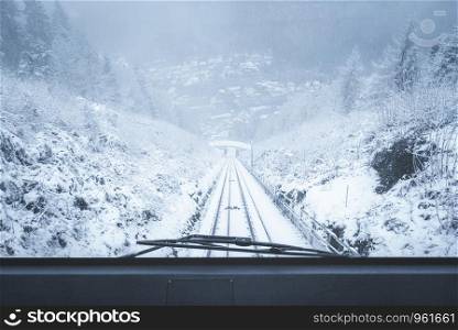 Moving funicular vehicle windshield view with snow-covered nature scenery in Bad Wildbad, Black Forest, Germany, on a snowy day of January.