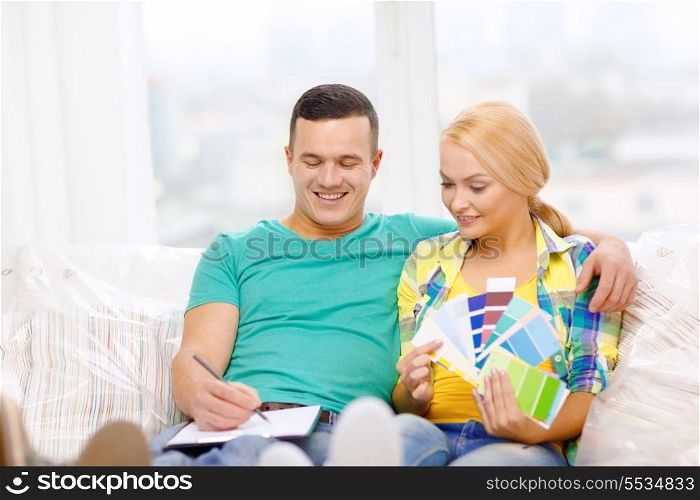 moving, home and couple concept - smiling couple looking at color samples in new home