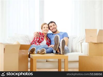 moving, home and couple concept - smiling couple relaxing on sofa in new home