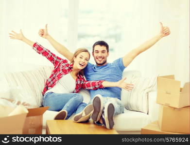 moving, home and couple concept - smiling couple relaxing on sofa in new home