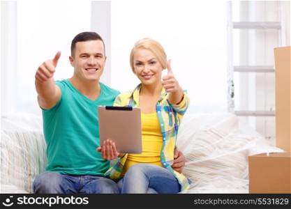 moving, home, technology and couple concept - smiling couple relaxing on sofa with tablet pc computer showing thumbs up in new home