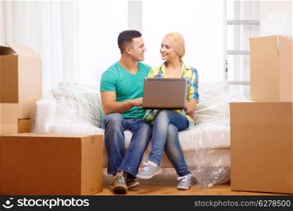 moving, home, technology and couple concept - smiling couple relaxing on sofa with laptop in new home