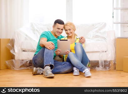 moving, home, technology and couple concept - smiling couple sitting on the floor with tablet pc computer in new home