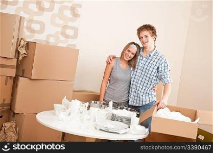Moving house: Happy man and woman with box and dishes in new home