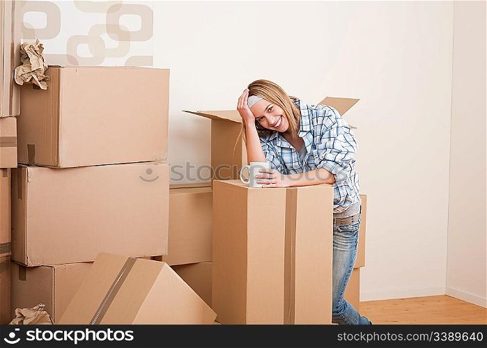 Moving house: Woman with box in new home having cup of coffee