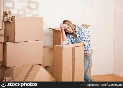 Moving house: Woman with box in new home having cup of coffee