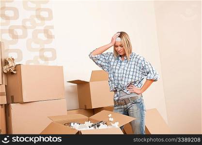Moving house: Young woman unpacking box with kitchen dishes