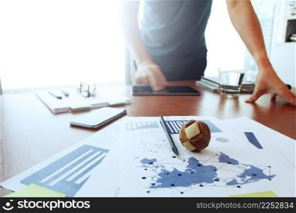 Moving Image of Business creative designer working wooden texture globe with smart phone on business document in office desk as internet concept