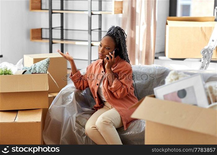 moving, people and real estate concept - angry woman with boxes calling on smartphone at new home. woman calling on phone moving to new home