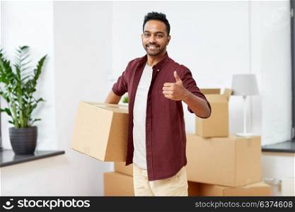 moving, people and real estate concept - happy indian man with boxes at new home showing thumbs up. man with box moving to new home showing thumbs up