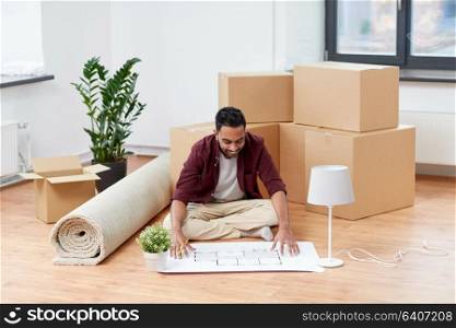 moving, people and real estate concept - happy indian man with boxes and blueprint at new home. man with boxes and blueprint moving to new home