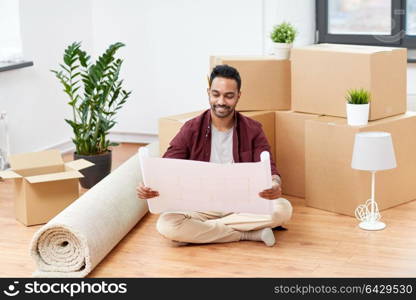 moving, people and real estate concept - happy indian man with boxes and blueprint at new home. man with boxes and blueprint moving to new home