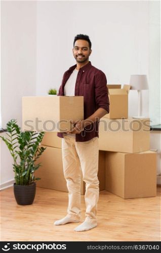 moving, people and real estate concept - happy indian man with boxes at new home. happy man with box moving to new home and dancing