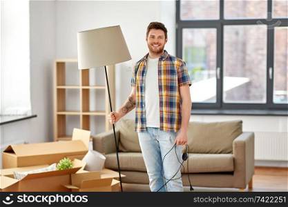 moving, people and real estate concept - happy man with floor lamp at new home. happy man with floor lamp moving to new home
