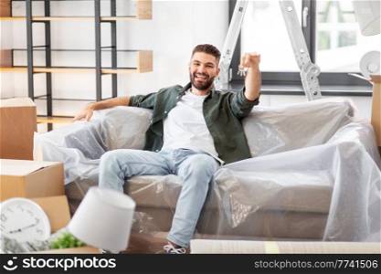moving, people and real estate concept - happy man with house keys and boxes at new home. man with house keys and boxes moving to new home