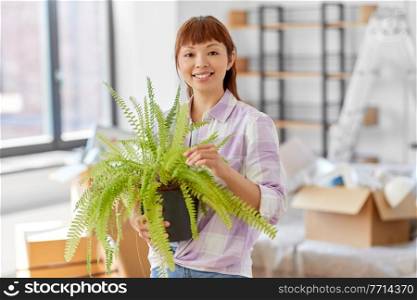 moving, people and real estate concept - happy smiling asian woman holding with fern flower in pot at new home. happy woman with fern flower moving to new home