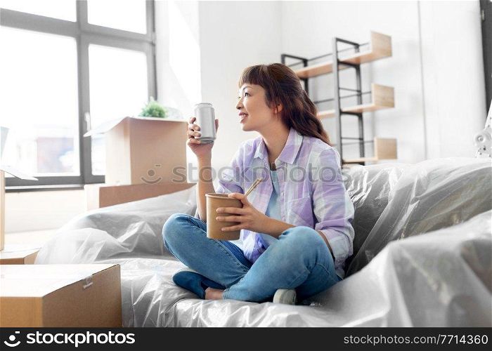 moving, people and real estate concept - happy smiling asian woman with boxes eating takeaway chinese food and drinking from tin can at new home. happy woman moving to new home and eating wok
