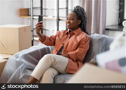 moving, people and real estate concept - happy smiling asian woman with smartphone taking selfie at new home. woman with smartphone taking selfie at new home