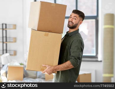 moving, people and real estate concept - happy smiling man holding boxes with stuff at new home. happy man with boxes moving to new home