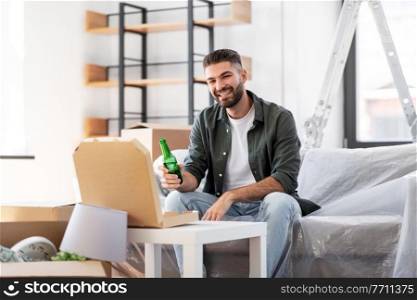 moving, people and real estate concept - happy smiling man with box of pizza and beer bottle at new home. man with box of pizza and beer bottle at new home