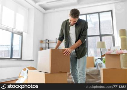 moving, people and real estate concept - happy smiling man with boxes with stuff at new home. happy man with boxes moving to new home