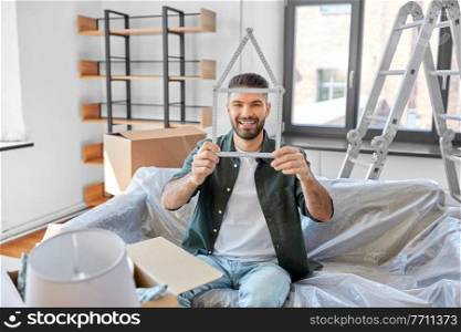moving, people and real estate concept - happy smiling man with ruler in shape of house boxes at new home. happy man with boxes moving to new home