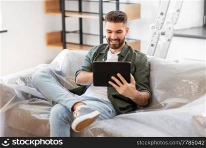 moving, people and real estate concept - happy smiling man with tablet pc computer at new home. man with tablet computer and moving into new home