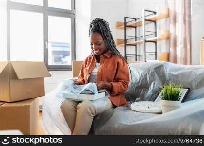 moving, people and real estate concept - happy smiling woman packing boxes sitting on sofa at home. happy woman packing boxes and moving to new home