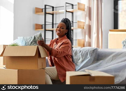 moving, people and real estate concept - happy smiling woman unpacking boxes sitting on sofa at new home. happy woman unpacking boxes with stuff at new home