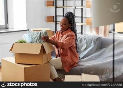 moving, people and real estate concept - happy smiling woman unpacking boxes sitting on sofa at new home. happy woman unpacking boxes with stuff at new home