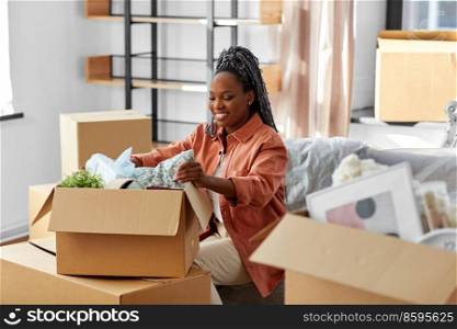 moving, people and real estate concept - happy smiling woman unpacking boxes sitting on sofa at new home. happy woman unpacking boxes with stuff at new home