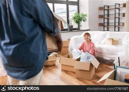 moving, people and real estate concept - happy smiling woman unpacking boxes at new home. woman unpacking boxes and moving to new home
