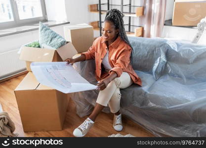 moving, people and real estate concept - happy smiling woman with blueprint and boxes at new home. woman with blueprint and boxes moving to new home