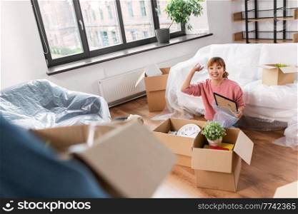 moving, people and real estate concept - happy smiling woman with boxes at new home throwing packing peanuts. woman unpacking boxes and moving to new home