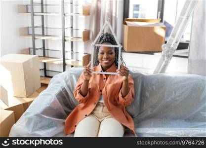 moving, people and real estate concept - happy smiling woman with ruler in shape of house at new home. happy woman with ruler moving to new home