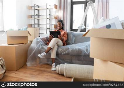moving, people and real estate concept - happy smiling woman with tablet pc computer and boxes at new home. smiling woman with tablet pc moving into new home