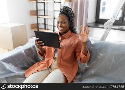 moving, people and real estate concept - happy smiling woman with tablet pc computer having video call at new home. smiling woman with tablet pc having video call