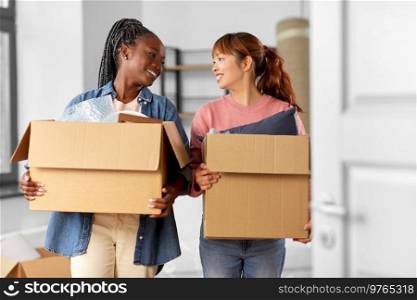 moving, people and real estate concept - happy smiling women with boxes at new home. women with boxes moving to new home