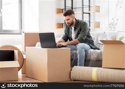 moving, people and real estate concept - man with laptop computer at new home. man with laptop computer and moving into new home