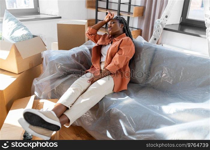 moving, people and real estate concept - tired woman with boxes sitting on sofa at new home. tired woman with boxes moving to new home