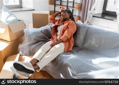 moving, people and real estate concept - tired woman with boxes sitting on sofa at new home. tired woman with boxes moving to new home